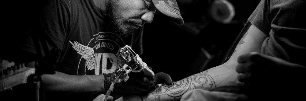 Tattooing an arm, photo by Kristian Angelo