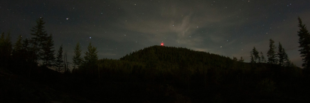 The Night Mothman Crashed On Black Mountain And Other Lies I Told Myself by Rachel Savage A mountain at night with a single light on top, photo by D. Benj