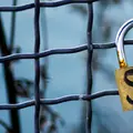 A padlock on a chain link fence, photo by Georgy Rudakov